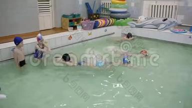 两个男孩正在游泳池里游泳。 在学校游泳池里游泳。 伙计们学游泳